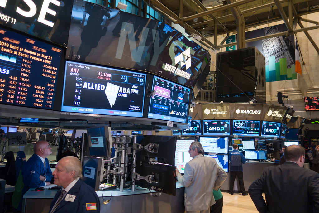 Traders on the New York Stock Exchange floor surrounded by ticker monitors.