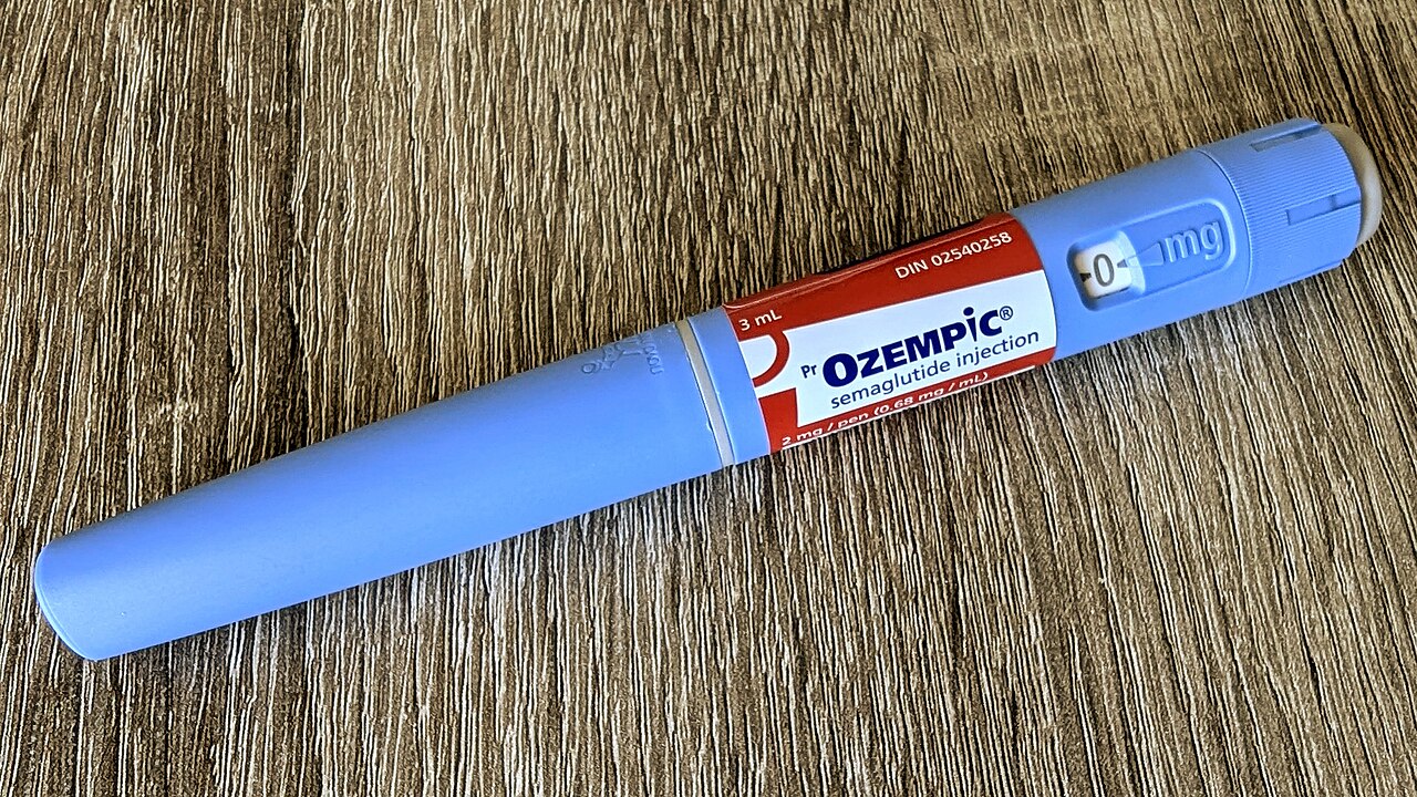 A blue Ozempic semaglutide injection pen resting on a wooden surface